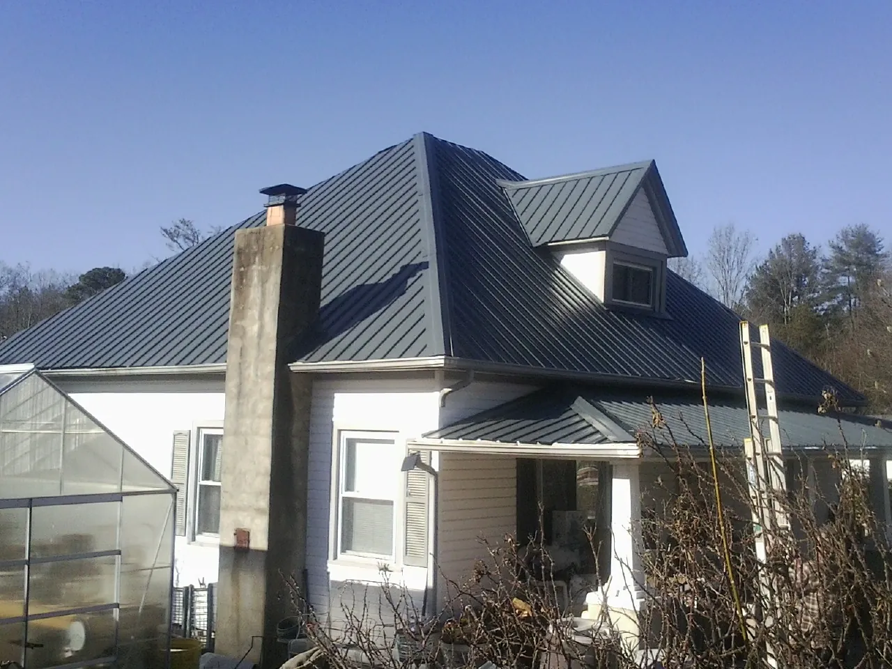 Dark blue standing seam metal roof on a white farmhouse with dormer — Slate & Tile Roof Repair by Roofing Brothers in Muscotah