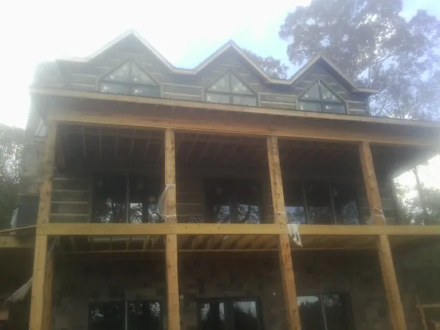 Dormers and porch framing on a large log home under construction — Roof Coating work by our crew in Muscotah