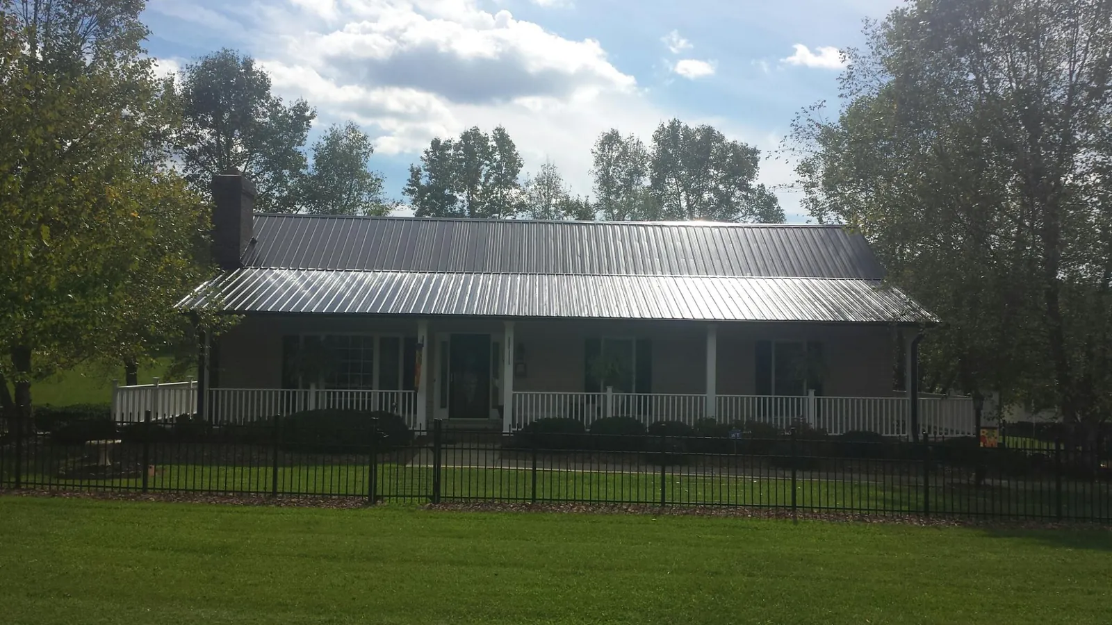 Gray metal roof on a brick ranch with a full width front porch — Gutter Guard Installation work by our crew in Muscotah