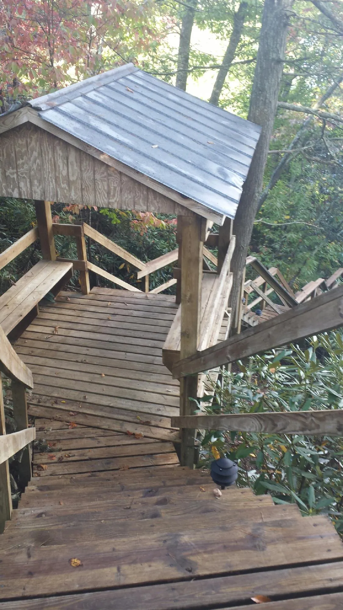 Metal roofed shelter over wooden steps on a wooded walkway — Skylight Repair & Installation work by our crew in Muscotah