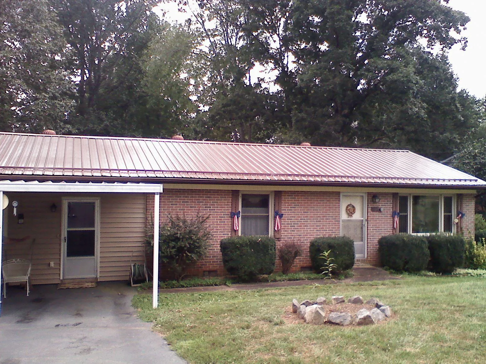 Bronze metal roof and carport on a brick ranch home — Roof Repair work by our crew in Muscotah