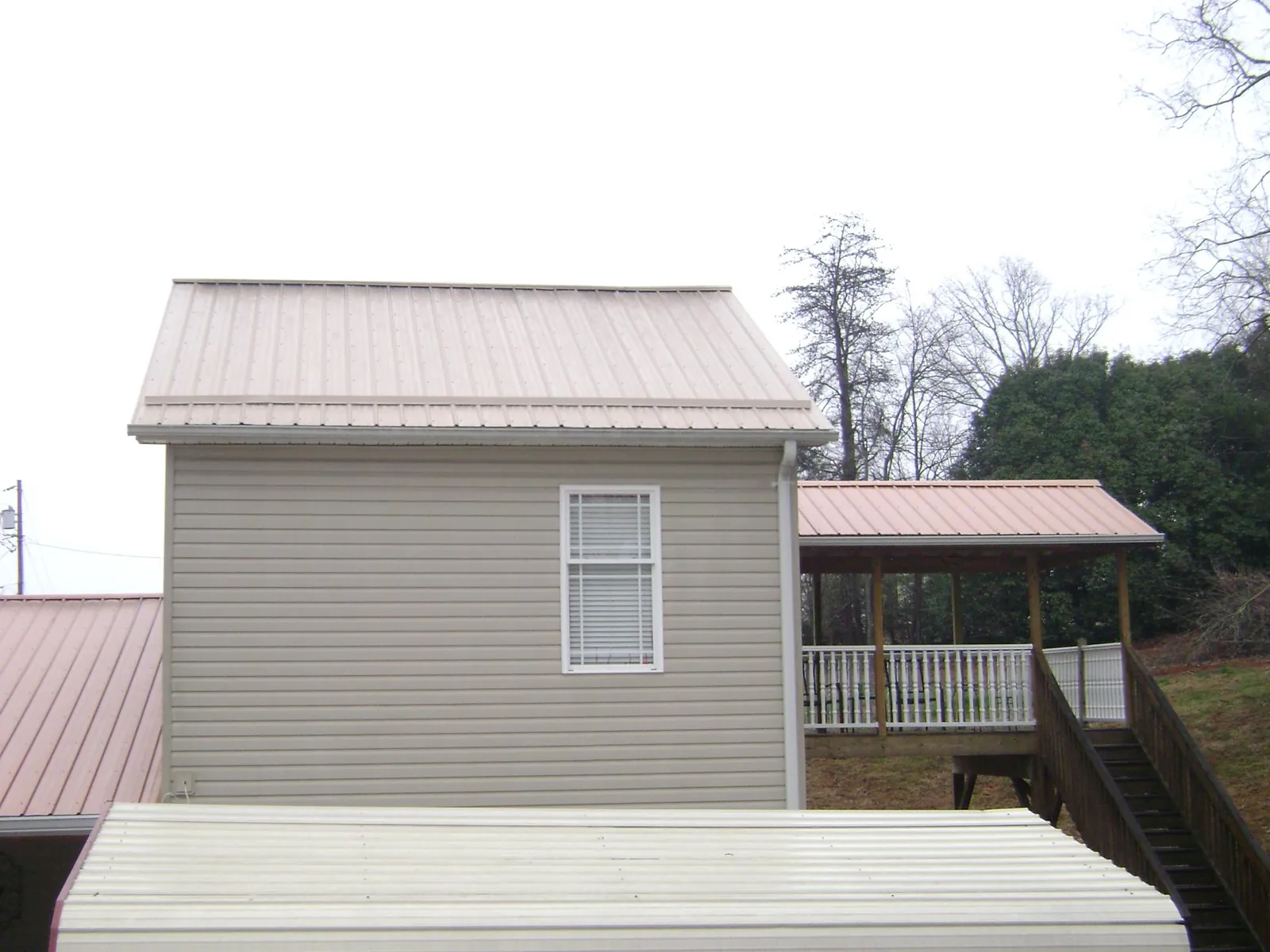 Tan metal roofs on a two story addition and attached porch, from a Roof Replacement job in Muscotah